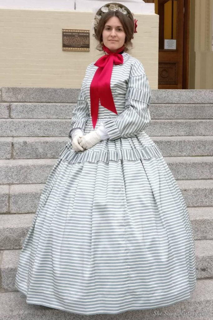 Reenactor portraying Queen Victoria's Lady in Waiting Baroness Lady Churchill in silk striped Day Dress and Bonnet