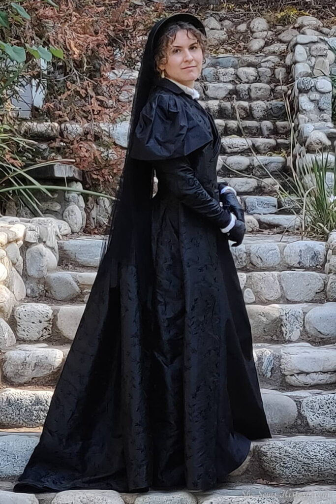 Black Silk 1880s Mourning Tea Gown and Bonnet with veil on stone steps