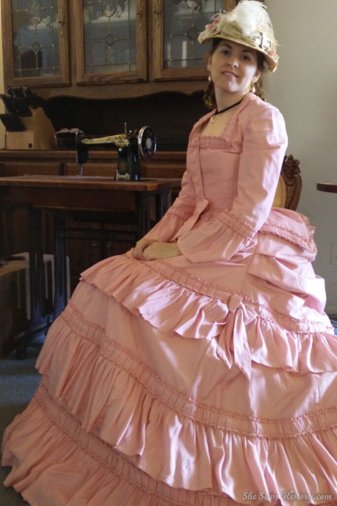 Girl seated in a Pink 1870 victorian day dress