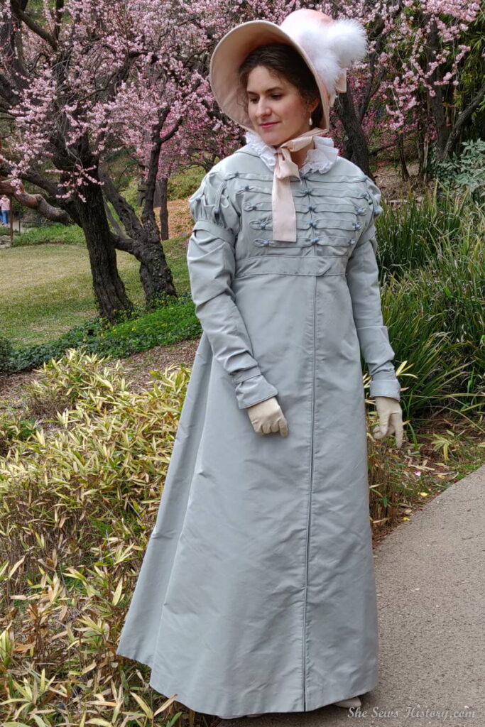 Woman in a garden in a Regency Pelisse and Silk Bonnet