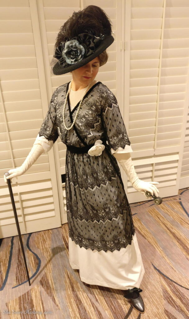 Woman in Lace Black and White Titanic Dress with walking stick and large hat